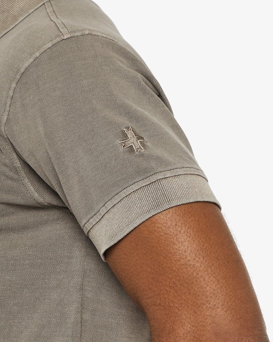 Polo in piquet garment dye, ricamo in tono su manica